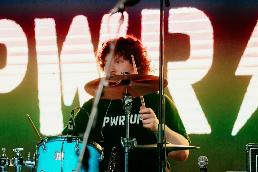 Andrew playing drums in front of a bright stage backdrop