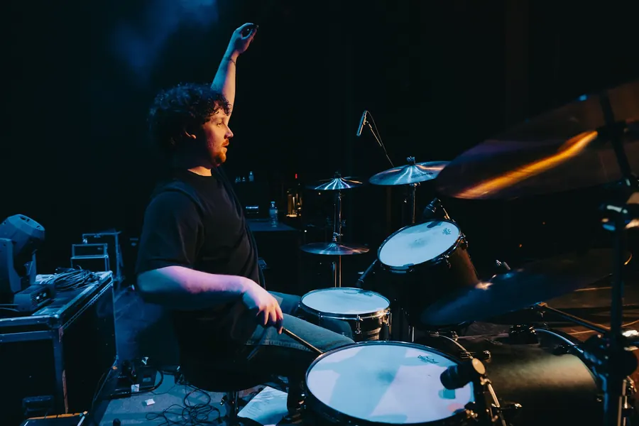 Andrew at the drums with one stick raised high